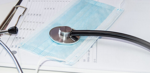 Medical protective mask and stethoscope on a white table in the doctor's office, close-up