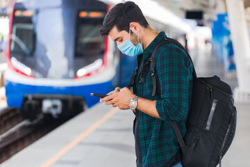 Caucasian man wearing surgical masks waiting to board the public train.