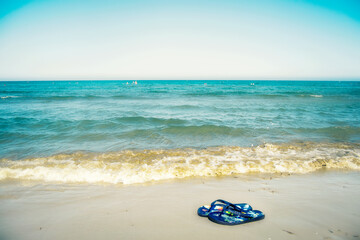 Fototapeta na wymiar Flip flops on the beach near the blue sea