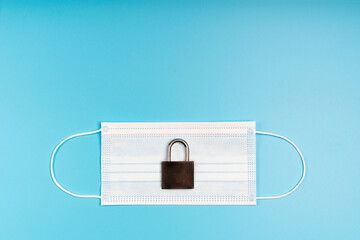 Medical mask and padlock. Concept of quarantine, protection, restriction from viruses and pandemic.