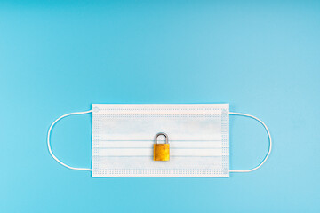 Medical mask and padlock. Concept of quarantine, protection, restriction from viruses and pandemic.