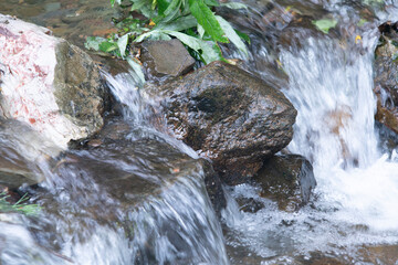 A seething stream of water flows over the stone boulders.