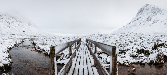 the bridge over the River Coupall at the foot of Buachaille Etive Mor and Lagarban cottage on rannoch moor in the argyll region of the highlands of scotland during winter