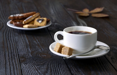 A cup of coffee and cake on a wooden background. Morning hot coffee and pastry on a wooden table. A white coffee cup and cane sugar. Steam.Espresso.