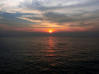 Beautiful orange sunset sky and ocean. The far distance have the silhouette of the boats.