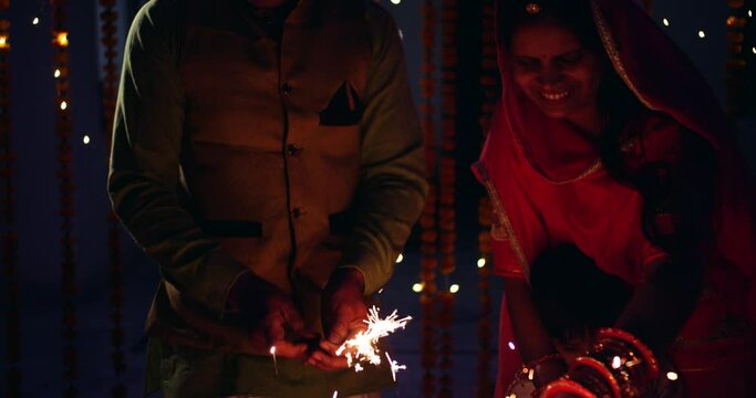 Slow motion portrait of a young couple with male boy wearing colorful traditional dress decorating with flowers, enjoying having fun for Diwali- traditional Indian Hindu festival of lights