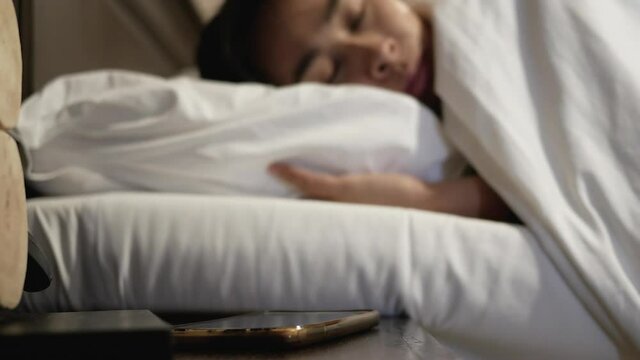 Asian woman tired sleepy in bed and turn off alarm clock sound in the morning.