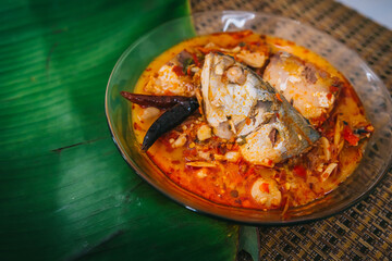Top view of spicy and hot king fish curry with herb and chili on wooden table, Thai food made from coconut milk and egg pant whit herbs, Fish curry