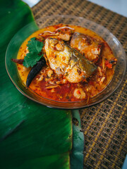 Top view of spicy and hot king fish curry with herb and chili on wooden table, Thai food made from coconut milk and egg pant whit herbs, Fish curry