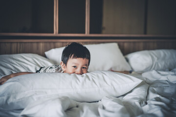 2 years old little boy dressed in Striped Tshirt are relaxing and lying down in bed, warm and cozy...