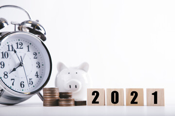 2021 New year saving money piggy bank with Wood word 2021 and Alarm clock. Money-saving concept
