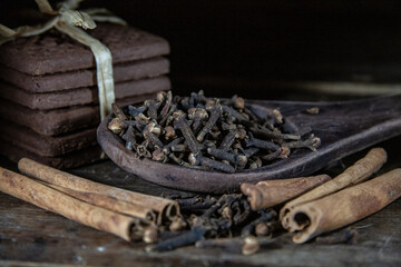 cloves in a wooden spoon and cinnamon
