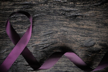 Top view of purple ribbon on wood background with copy space. Pancreatic cancer, epilepsy,...