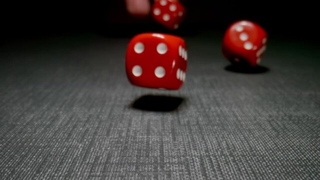 MACRO: Human hand throws red cubes on a dark surface, slow motion