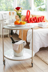 Glasses of champagne, fruits and flowers on table in hotel honeymoon room