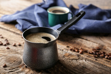 Cezve with coffee on wooden table