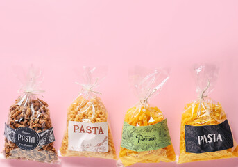 Bags with uncooked pasta on color background
