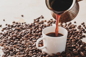 Pouring coffee from cezve in cup on table