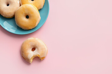 Plate with tasty donuts on color background