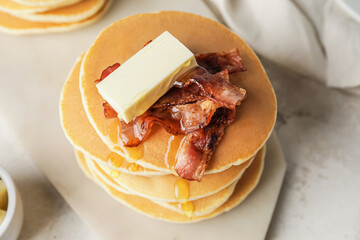 Tasty pancakes with butter and fried bacon on table