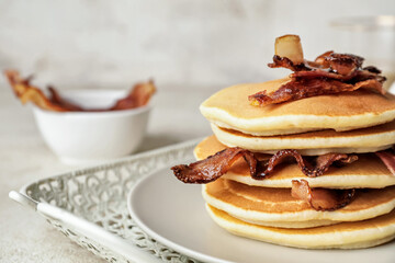 Plate of tasty pancakes with fried bacon on table