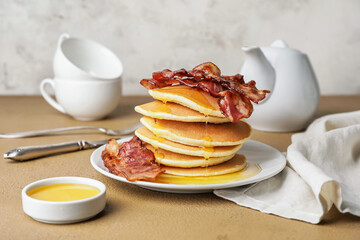 Plate of tasty pancakes with fried bacon on table