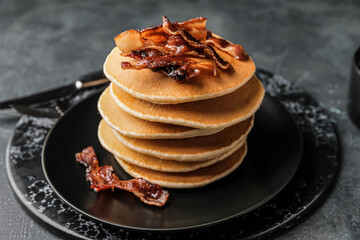 Plate of tasty pancakes with fried bacon on table