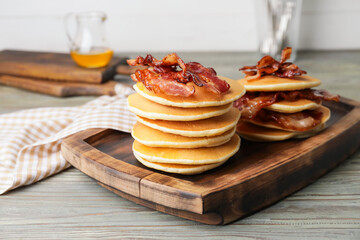Tasty pancakes with fried bacon on wooden table