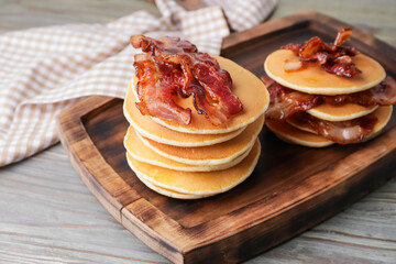 Tasty pancakes with fried bacon on wooden table