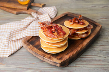 Tasty pancakes with fried bacon on wooden table
