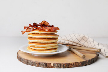 Plate of tasty pancakes with fried bacon on table