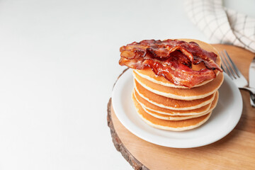 Plate of tasty pancakes with fried bacon on table