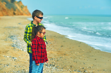 Two children on a walk by the sea on a cool day