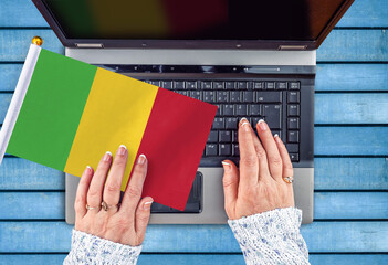 woman hands and flag of Mali on computer, laptop keyboard
