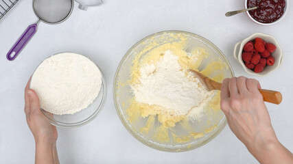 Christmas shortbread cookies with raspberry preserves recipe. Chef mixing ingredients in a glass bowl, close up view from above