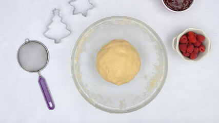 Cookie dough in a glass bowl. Shortbread cookies with raspberry jam close up baking process.