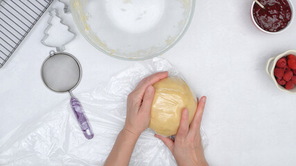 Cookie dough. Chef covers dough with plastic wrap. Shortbread cookies with raspberry jam close up baking process.