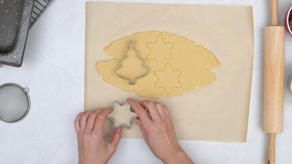 Christmas shortbread cookies with raspberry jam recipe. Chef using cookie cutters to stamp Christmas cookies, pine tree cutter and star cutter