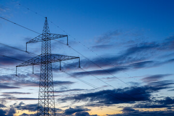 Metal tower and high voltage power lines with sky and clouds at sunset. Province of León, Spain.