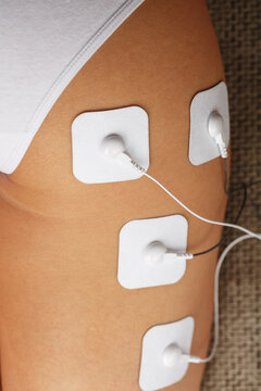 Myostimulation electrodes on the buttocks and legs of a woman in a beauty salon.