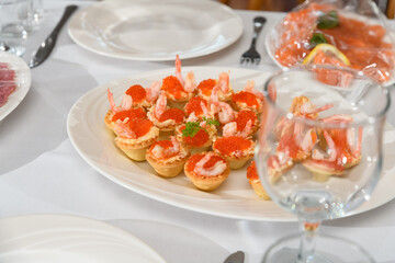 tartlets with red fish eggs, shrimp and butter on the festive table