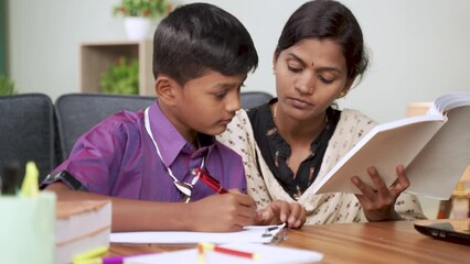 Indian Mother helping son to do school homework - concept of parental support for education during childhood