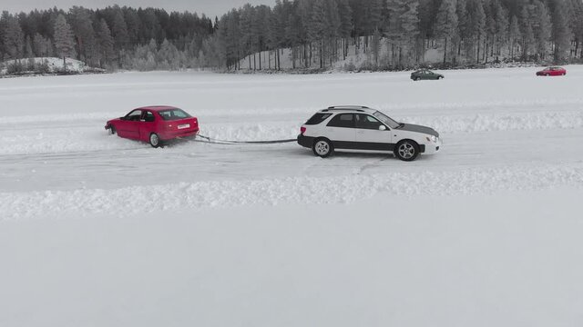 Car trying to pull car out of thick snow on drifting race track in Norway