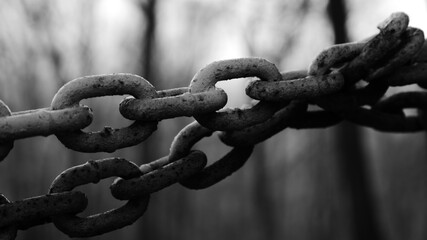 Black and white close up of think iron chains against a blurry background