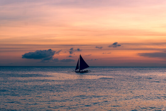 Beautiful sunset with a view of a local paraw saliboat in Boracay Island in the Philippines.  Travle and holiday.
