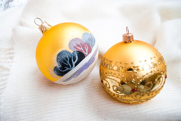 Gold Christmas toys on white knitted blankets. Golden painted balls newyear decor, selective focus