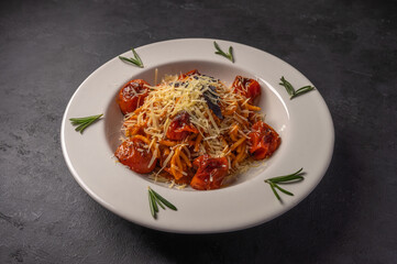Pasta with cherry tomatoes, cheese and rosemary served on plate on dark textured background, copy space