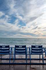 Fototapeta premium Chaises bleues face à la mer méditerranée à Nice sur la Promenade des Anglais en France