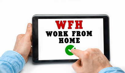 Closeup of a male hands holding tablet pc with word WFH - Work From Home