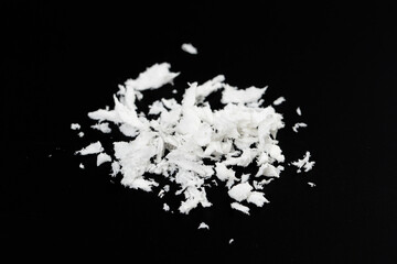 a pile of poured white artificial synthetic snow on a black background